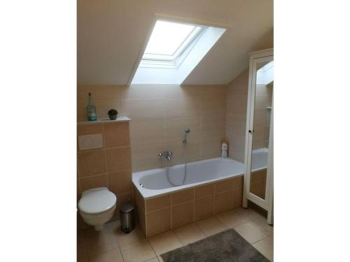 a bathroom with a tub and a toilet and a skylight at Seagull Street 21 Merchant in Horumersiel
