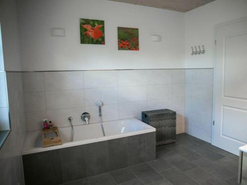 uma banheira numa casa de banho com duas fotografias na parede em Holiday home Birx Rhön em Birx