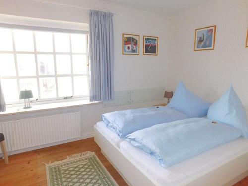 a bedroom with a bed with blue sheets and a window at Haus Hoppel - FeWo ground floor in Rantum