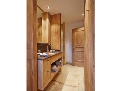 uma cozinha com armários de madeira, um lavatório e um espelho em Chestnut in chalet Bergerhöh em Bad Wiessee
