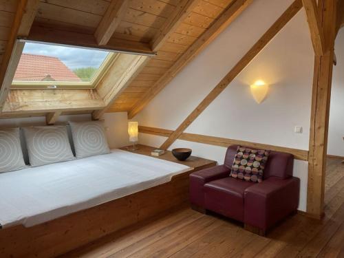 ein Schlafzimmer mit einem Bett und einem Stuhl im Dachgeschoss in der Unterkunft Schleichhof Ammersee in Dießen am Ammersee