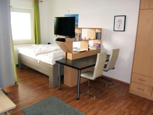 Zimmer mit einem Schreibtisch, einem Bett und einem Schreibtisch mit einem TV. in der Unterkunft "At Low 8" Merchant in Horumersiel