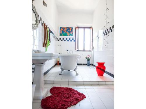 ein Badezimmer mit einer weißen Badewanne und einem roten Teppich in der Unterkunft Casa La Fonte - Olivastra in Seggiano