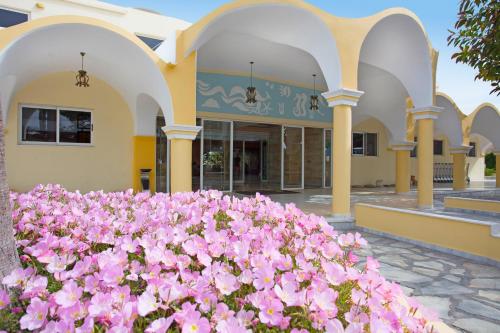 a bunch of pink flowers in front of a building at Eurovillage Achilleas Hotel in Mastichari