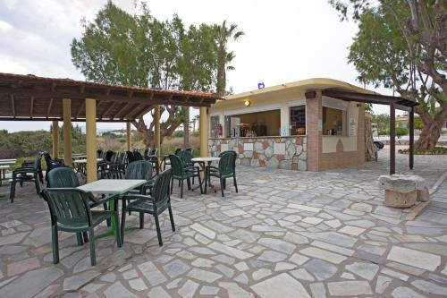 a patio with tables and chairs and a building at Eurovillage Achilleas Hotel in Mastichari