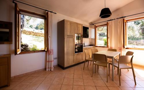 a kitchen and dining room with a table and chairs at Welcomely - Badde Nuraghe dimora vista mare con parcheggio privato in Magomadas