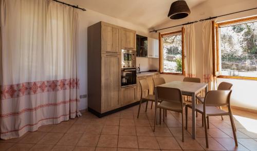 a kitchen and dining room with a table and chairs at Welcomely - Badde Nuraghe dimora vista mare con parcheggio privato in Magomadas