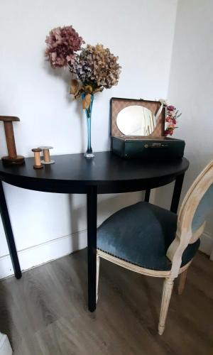 a table with a vase of flowers and a chair at La Villa Beausejour in Baives