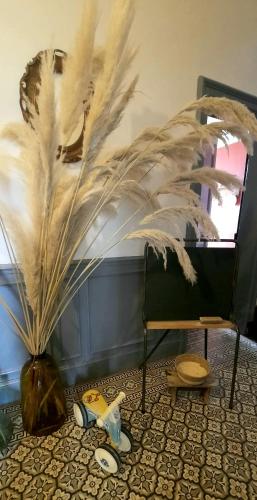 a vase with feathers on the floor next to a chair at La Villa Beausejour in Baives