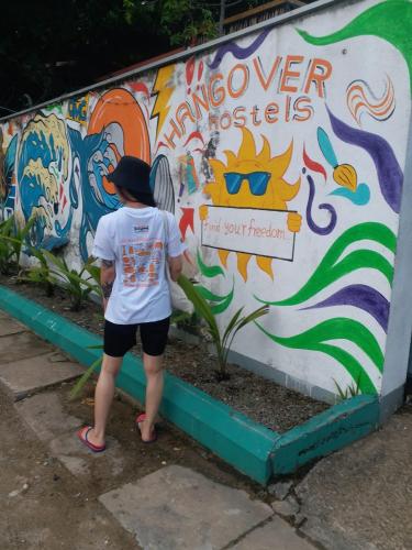 a person standing in front of a wall covered in graffiti at Hangover Hostels Mirissa in Mirissa