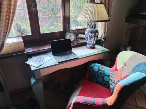 a desk with a laptop on it next to a chair at L'Agrifoglio di Assisi Residenza di Campagna in Assisi