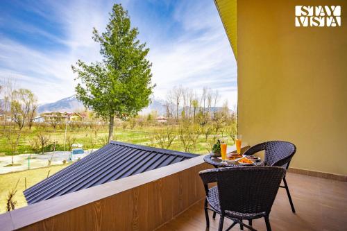 a balcony with two chairs and a table with drinks on it at The Dewan Bagh with Heater at Srinagar by StayVista in Srinagar