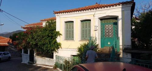 un hombre parado frente a una casa con una puerta verde en Traditional Stone House, en Koustáros