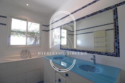 Somptueuse Villa l'Oasis By HC في كاركيران: حمام مع حوض أزرق ومرآة