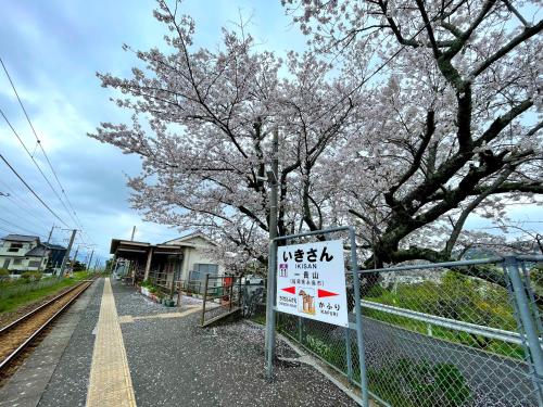 a sign on a fence next to a tree with flowers at 田辺ハウス in Kafuri