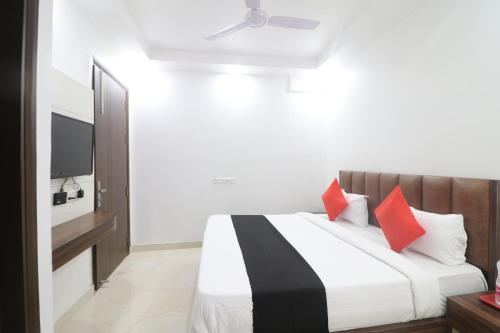 um quarto com uma cama com almofadas vermelhas e uma televisão em Hotel Golden Prime em Nova Deli