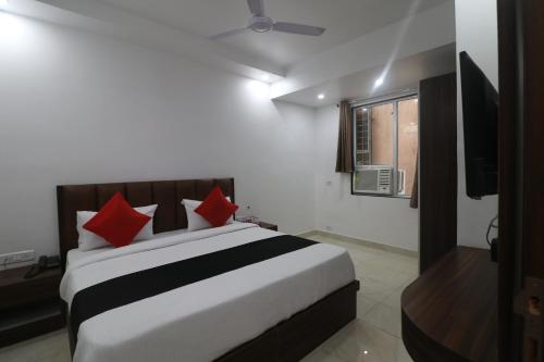 1 dormitorio con 1 cama grande con almohadas rojas en Hotel Golden Prime, en Nueva Delhi