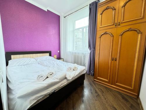 a bedroom with a bed with a purple wall at City Center Apartments on Tumanyan street in Yerevan