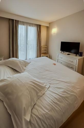 a large white bed in a bedroom with a television at Tulip Inn Honfleur Residence & Spa in Honfleur
