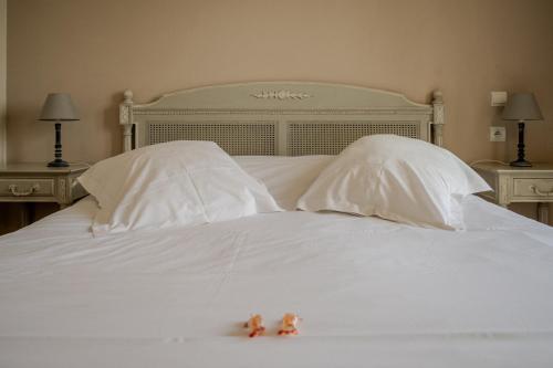 a white bed with two stuffed animals on top of it at Tulip Inn Honfleur Residence & Spa in Honfleur