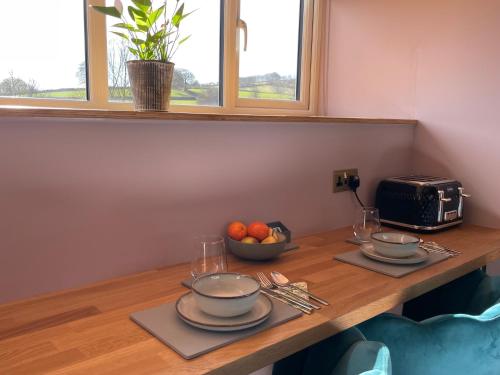 a table with two plates and a bowl of fruit on it at The Hayloft, Exmoor in Withypool