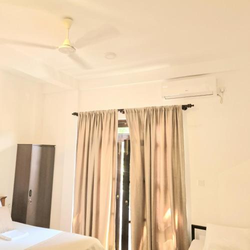a room with two beds and a window at Mamma Mia Villa and Cafeteria in Unawatuna