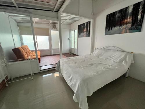 a bedroom with a bed and a balcony with a chair at Villa88 in San Kamphaeng