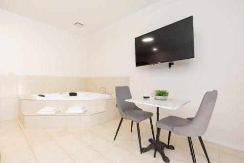 a bathroom with a sink and a table and chairs at Comfort Inn Deakin Palms in Mildura