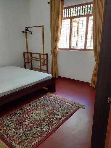 a bedroom with a bed and a rug and a window at Kandy Breeze Stay in Urulewatta