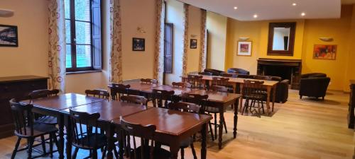 une chambre avec des tables, des chaises et une cheminée dans l'établissement Le Porteur de Glace Classé 2 étoiles, à Aulus-les-Bains