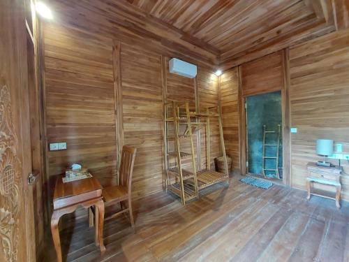 ウブドにあるD'Ethnic Ubud Joglo View Villas by EPSのテーブルとデスクが備わる木製の壁の客室です。