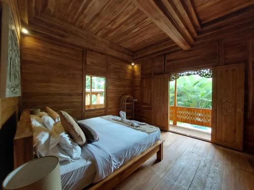 ウブドにあるD'Ethnic Ubud Joglo View Villas by EPSの木製の部屋にベッド1台が備わるベッドルーム1室があります。