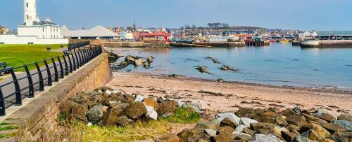 a beach with rocks and a lighthouse in the water at Red Lion Caravan Park, Arbroath in Arbroath