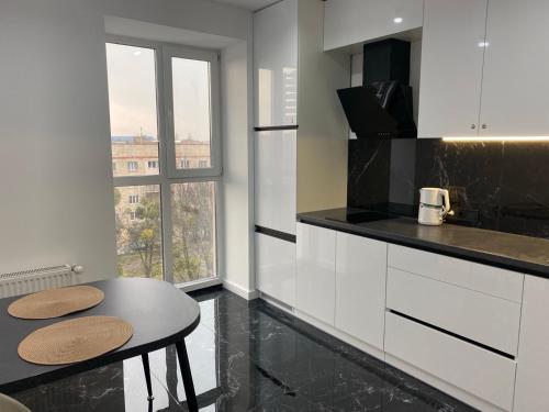 una cocina con armarios blancos y una mesa con dos taburetes en ВІП Апартаменти в районі автовокзалуЖК Great House,ЖК Арена,ПОБЛИЗУ ОБЛАСНОІ ЛІКАРНІ, en Rivne