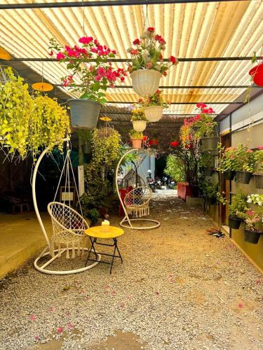 three chairs and a table in a greenhouse with flowers at Angkor Piseth Homestay in Siem Reap