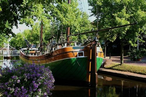 a boat sitting in the water next to some flowers at WH Hotels Papenburg Zentrum in Papenburg