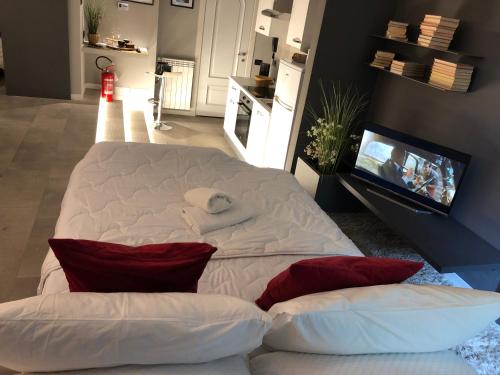 a large white bed with red pillows and a tv at Molino nuovo in Maslianico