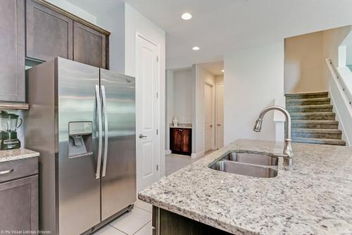 La cuisine est équipée d'un réfrigérateur en acier inoxydable et d'un évier. dans l'établissement 8 Bedroom Vacation Home with Pool 2114, à Orlando