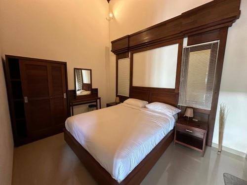 a bedroom with a large bed with a wooden headboard at Bukit Kembang Sari in Bugbug