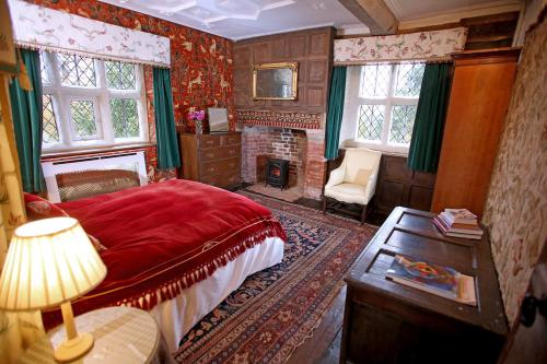 een slaapkamer met een rood bed en een open haard bij Chevaliers Gatehouse in Morville