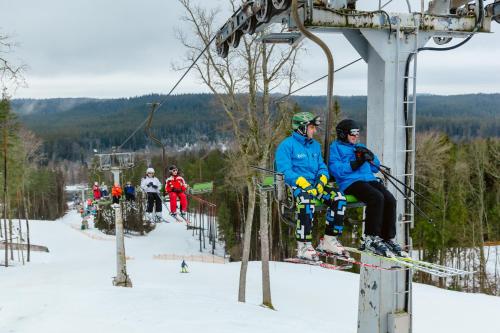 a group of people sitting on a ski lift at Kempings Ozolkalns in Cēsis