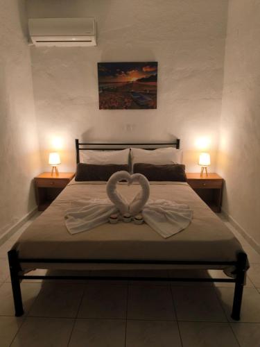 two heart shaped towels on a bed with two lamps at Falirakion Beach Studios in Faliraki