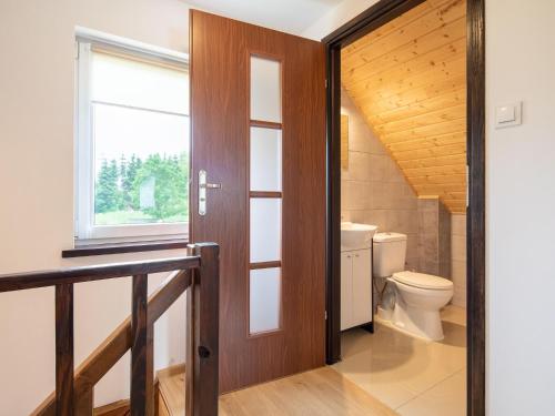 a bathroom with a toilet and a wooden door at Brick Cottage near Baltic Sea and Windmill in Lędzin