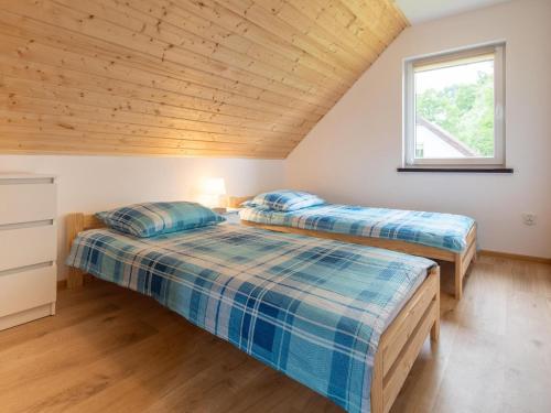 two beds in a bedroom with a wooden ceiling at Brick Cottage near Baltic Sea and Windmill in Lędzin