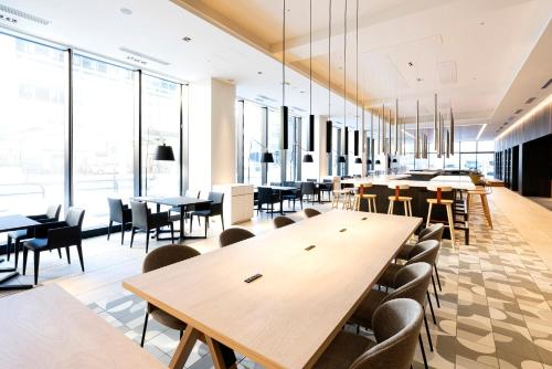 a cafeteria with tables and chairs and windows at Hotel JAL City Toyama in Toyama