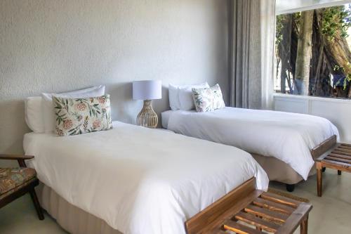 two beds in a bedroom with a window at Brinkley's River Village in Klein Brak Rivier