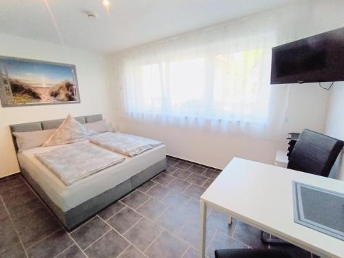 Un dormitorio con una cama, un escritorio y un televisor. en BodenSEE Apartments Fischbach Eichenmühleweg, en Fischbach