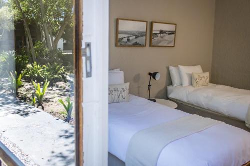 two beds in a room with a view of the beach at Brinkley's River Village in Klein Brak Rivier