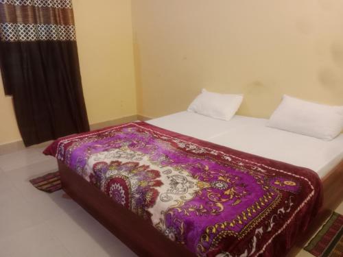 - un lit avec une couverture violette et blanche dans l'établissement Aanand Bhwan, à Ayodhya