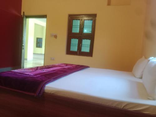 - une chambre avec un grand lit blanc et une fenêtre dans l'établissement Aanand Bhwan, à Ayodhya